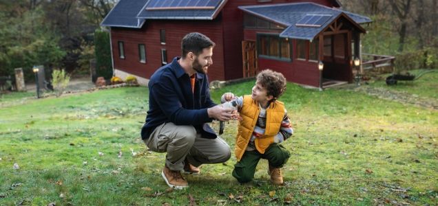 Father and son are playing in front of an energy-efficient house